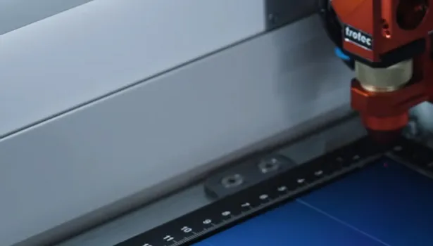Trotec laser cutter engraving lines on blue material with precision head