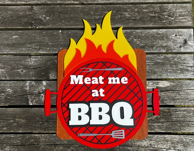 Buntes BBQ-Schild mit Laserschneider von Trotec mit Flammen und graviertem Text auf geschichtetem Acryl