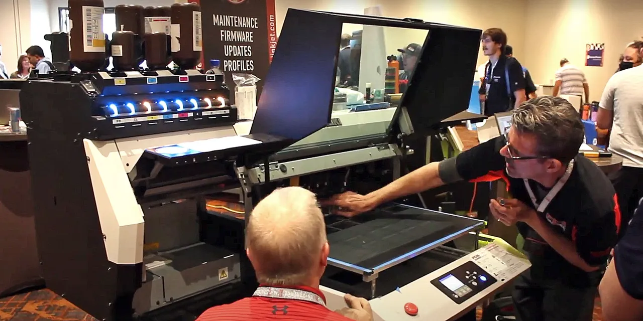 Technician demonstrating large format printer operation at trade show booth