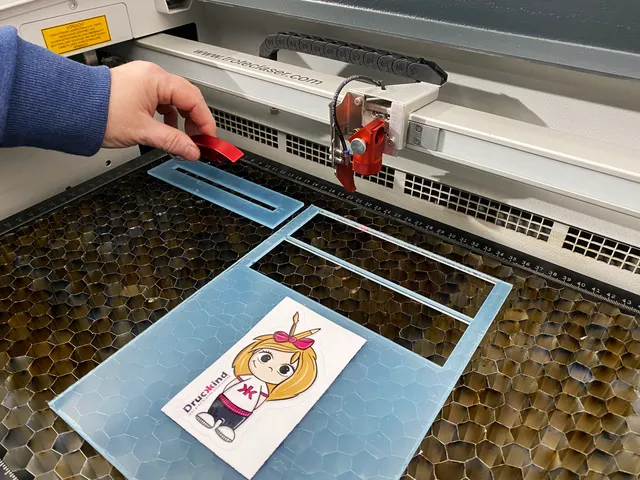 Trotec CO₂ laser cutter processing acrylic sheet with cartoon graphic using Speedy series machine