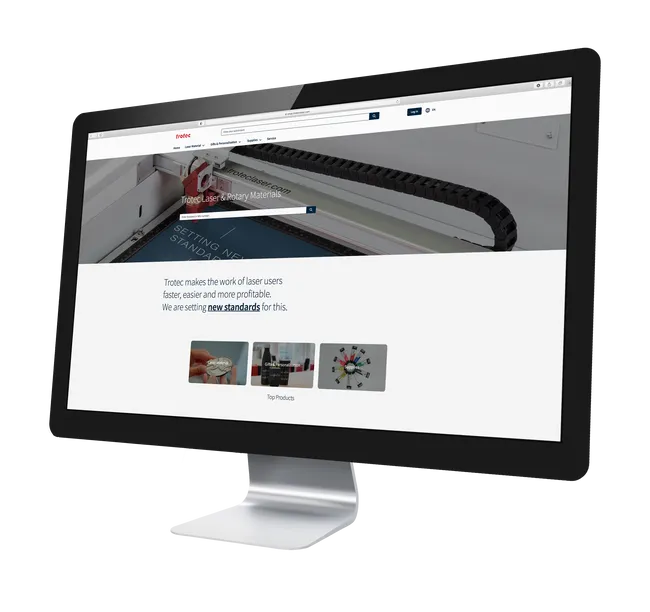 Trotec website displayed on a monitor featuring laser engraving materials and Speedy series machine