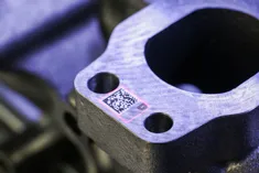 La machine SpeedMarker® de Trotec marque au laser un code Data Matrix sur un composant métallique de moteur.