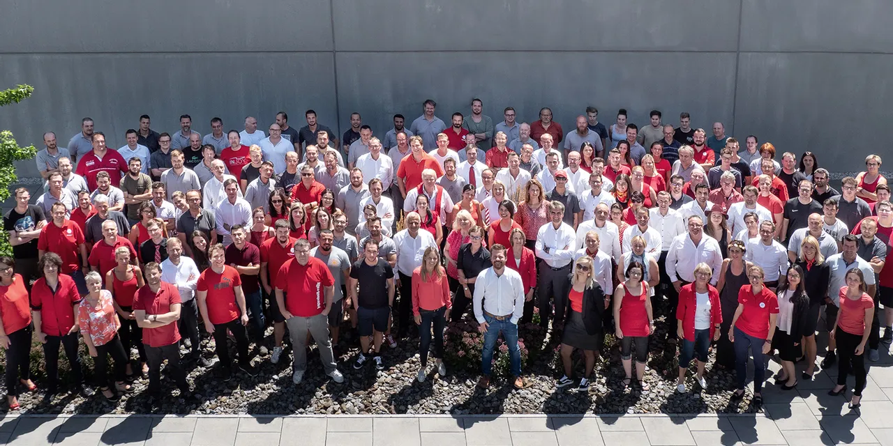Gran grupo de miembros del equipo de Trotec reunidos frente a la sede corporativa