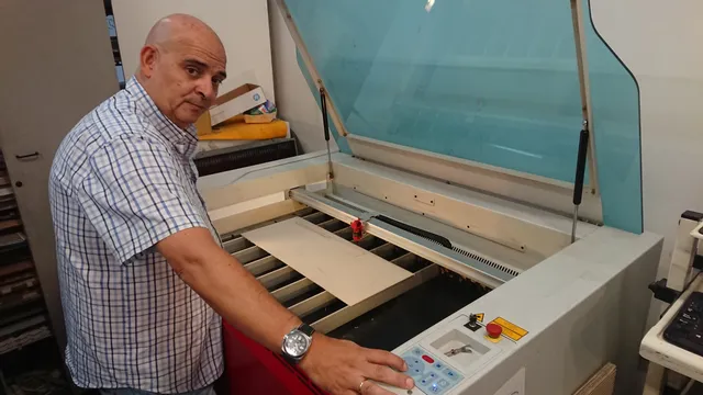 Hombre operando la máquina de grabado láser Trotec con CO₂ láser cortando material de lámina