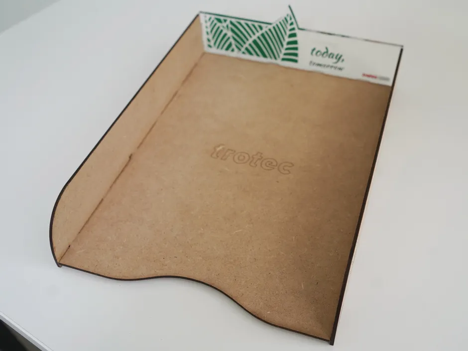 Bandeja portadocumentos de madera cortada con láser y grabada con el logotipo de Trotec mediante cortadora láser de CO₂.