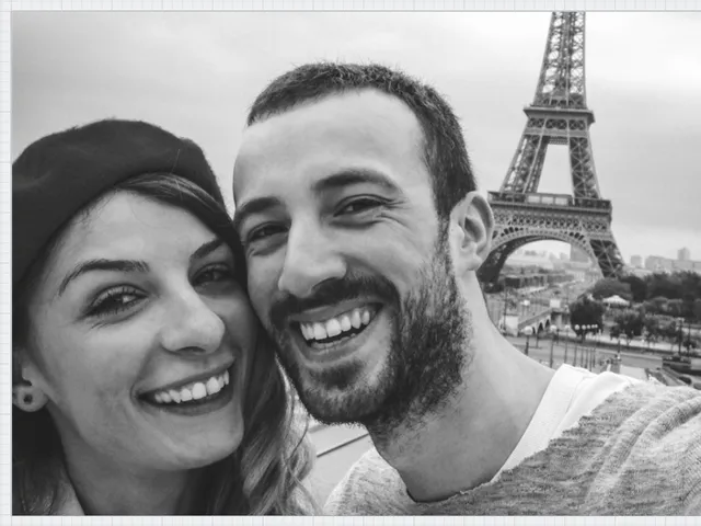 Smiling couple taking selfie with Eiffel Tower in background in Paris
