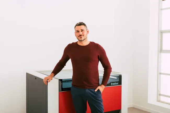 Man standing beside Trotec Speedy 400 CO₂ laser cutter in modern workspace