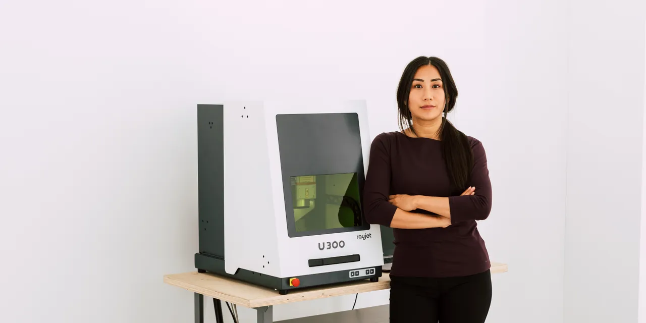 Frau steht neben dem Laserbeschriftungssystem Trotec U300 in einem modernen Arbeitsraum