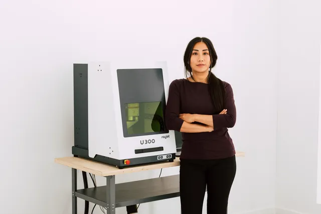 Donna in piedi accanto alla macchina di marcatura laser Trotec U300 in uno spazio di lavoro moderno